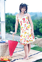 Standing on matting holding parasol in flowered dress